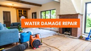 Living room undergoing water damage repair, featuring a blue couch, drying equipment, and a visible fireplace, with prominent text overlay reading "WATER DAMAGE REPAIR."