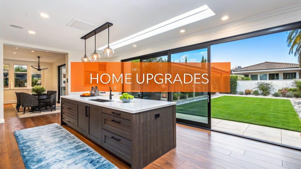 Modern kitchen interior showcasing home upgrades, featuring a stylish island, pendant lighting, and an outdoor view of a landscaped yard, overlaid with the text "HOME UPGRADES."