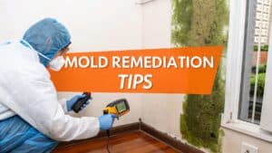 Mold remediation tips with technician in protective gear using a moisture meter near mold growth on wall, relevant to Orange County mold remediation guide for homeowners.