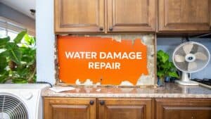 Water damage repair sign displayed in a kitchen cabinet, highlighting restoration needs for water-damaged cabinetry.